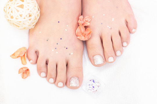 Female legs on a white background. Nails get a fresh and neat look during the pedicure procedure. Close up of female legs in spa salon.