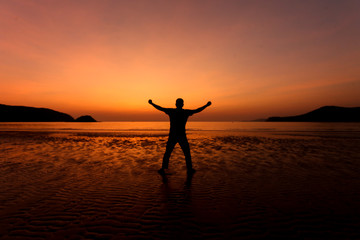 Fototapeta premium Silhouette action of a young man fun under twilight sunset sky at sea beach.