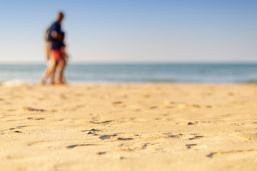 Holiday concept. Clear sand with blur guy, sea and clear sky background. Soft focus and focus selective sand.