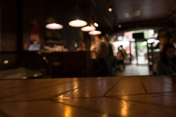 Image of wooden table in front of abstract blurred restaurant lights background