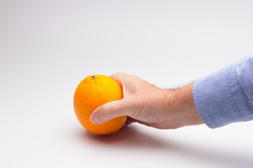 Naranja entera en la manode una persona adulta; naranja madura y preparada para ser consumida.