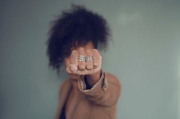 Closeup and selective focus on a black woman fist (with rings). Afro puff hair.