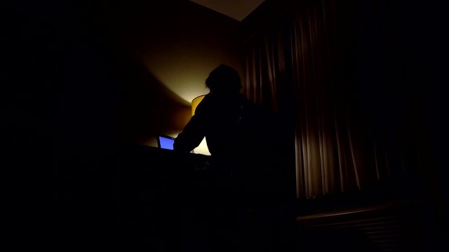 Low angle view of man sitting in front of computer in a dark room