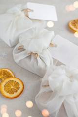 Christmas presents wrapped with white furoshiki fabric, labels and dried orange slices. Eco friendly gift.