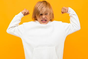 strong blond boy in a white hoodie on an orange background