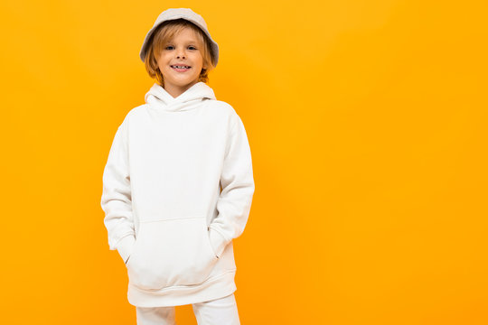 European boy with a panama in a light hoodie on an orange background