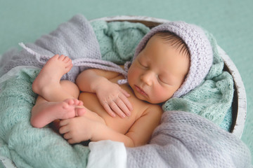 Newborn. Newborn boy sleeps in a basket. Gray-green colors.