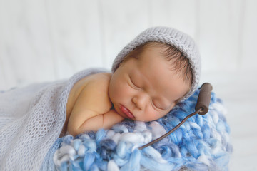 Newborn baby boy. Newborn is sleeping in a basket. Boy in blue on a white background.