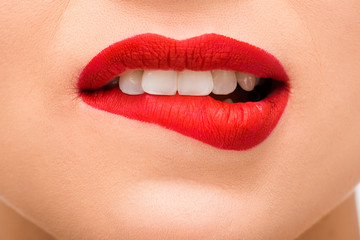 cropped view of sexy young woman with red lipstick biting lips
