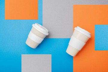 Two eco friendly reusable bamboo cups on orange blue grey background, top view, selective focus