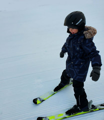 a child of European appearance, in warm clothes, a helmet, skiing in the snow. Security, protection, courage,active lifestyle 