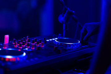 Fototapeta na wymiar club dj plays music on stage in nightclub.Hand of disc jockey adjusting sound track volume level.Professional audio equipment on music festival