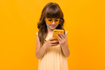 girl makes reads messages from the phone on a yellow background