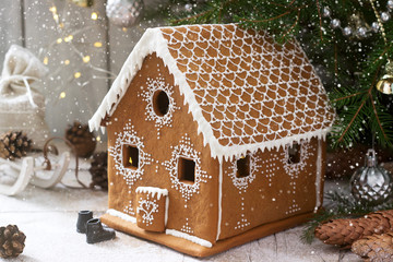 Gingerbread house and Christmas trees on a luminous background. Bokeh effect.