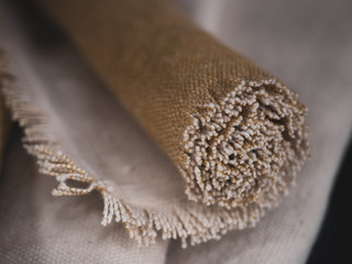 Frayed rolled up textile rug, coarse fabric