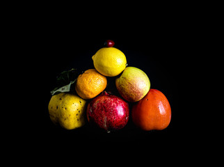 Fototapeta na wymiar Pyramid of fresh, ripe and coloured fruit on black background