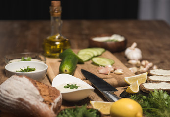 Tzatziki sauce with bread and raw vegetables on kitchen table