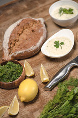 Homemade tzatziki sauce with bread and raw ingredients on wooden table