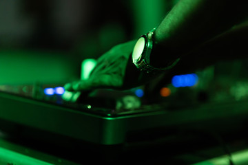 club dj plays music on stage in nightclub.Hand of disc jockey adjusting sound track volume...