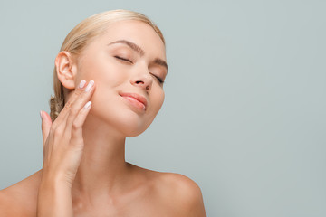 happy woman touching clean face isolated on grey