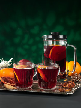 Mulled wine in a cafetiere or french press, with glasses on a silver tray, with pine cones and dried orange slices