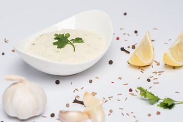 Delicious tzatziki sauce with garlic, lemon and spices on white background