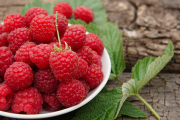 ripe raspberries with leaves on a wooden background. Space for text.