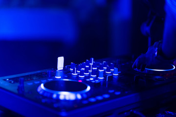 Fototapeta na wymiar club dj plays music on stage in nightclub.Hand of disc jockey adjusting sound track volume level.Professional audio equipment on music festival