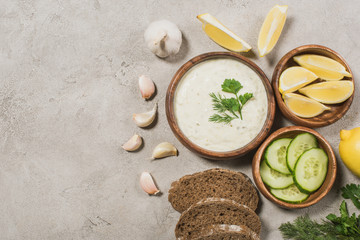 Top view of tzatziki sauce with bread and organic ingredients on stone background