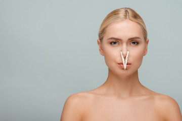 beautiful and naked young woman with wooden pin on nose isolated on grey - obrazy, fototapety, plakaty