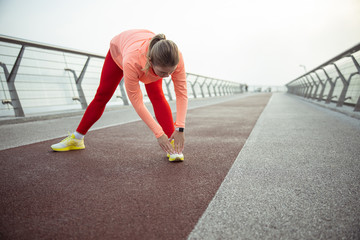 Sporty young lady stretching on the street