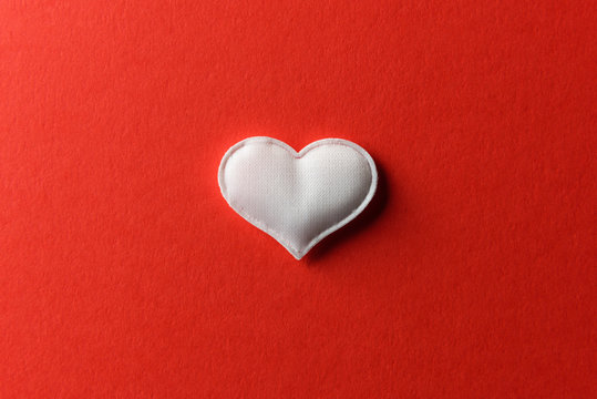 White textile heart on red background. Valentines day texture and love concept
