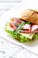 Sandwich with ham, cheese and lettuce. Bright wooden background. 