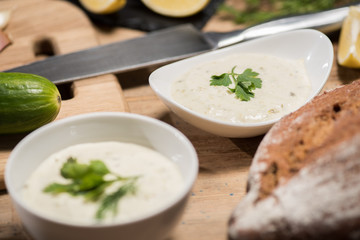 Selective focus of bowls with tzatziki sauce with bread on wooden table