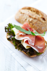 Sandwich with ham, cheese and lettuce. Bright wooden background. 