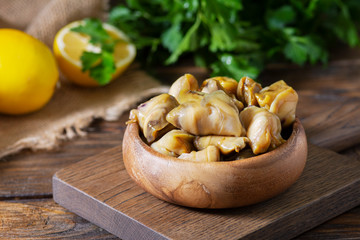 Meat rapan in a wooden bowl on a wooden table. Seafood, meat rapana