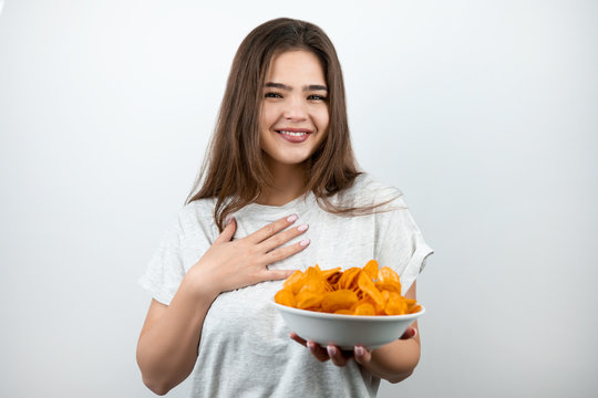 young attractive happy woman holding plate with spicy potatoe chips looking surprised on isolated white background dietology and nutrition