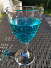 ice-cold blue juice cocktail on table in summer sun, blue lagoon summer cocktail