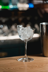 bar accessories shaker and full of ice cocktail glass on a bar background