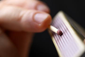 Male hands going to strat fire striking match