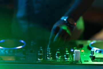 Obraz premium club dj plays music on stage in nightclub.Hand of disc jockey adjusting sound track volume level.Professional audio equipment on music festival