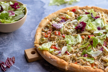 Pizza with chicken breast barbecue tomatoes and herbs on a wooden board