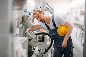 Tired factory worker. Man with helmet working.