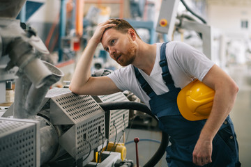Tired factory worker. Man with helmet working.