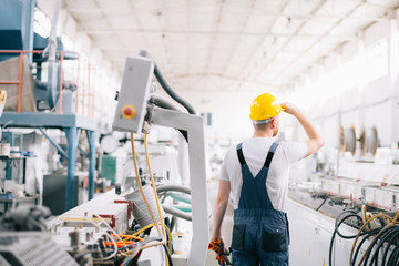 Factory worker. Man with helmet working on wires.	