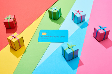 empty credit card and multicolored gift boxes on rainbow background