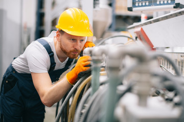 Factory worker. Man with helmet working on wires.	