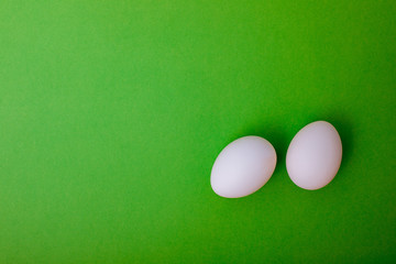 White chicken eggs are on green background. Easter card greeting. Flat lay. Copy space.