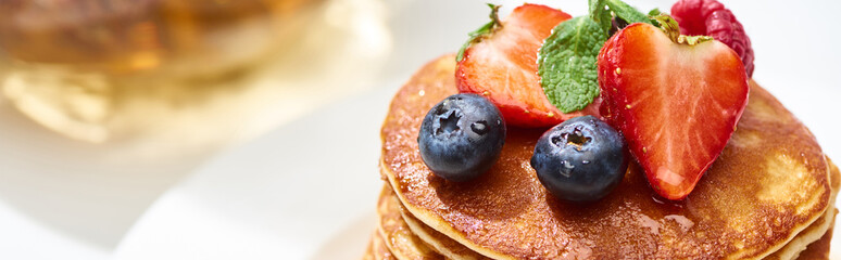 close up view of delicious pancakes with honey, blueberries and strawberries, panoramic shot
