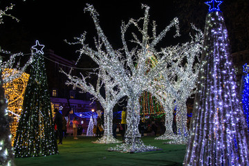 Colorful Christmas decorations and lights by night, New Year holiday decor, Varna city main square, people silhouettes